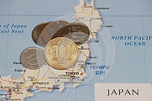 Heap of Japanese Yen coin money put on the Japan map. Concept of finance or travel