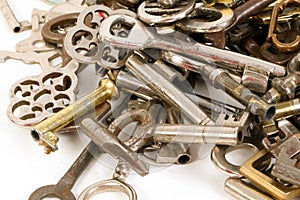 A heap of many different old keys are lying in the whiite studio photo