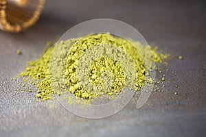 Heap of matcha green tea powder on darck background, close up with copy space