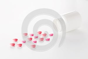 Heap of medical pills in red colors and plastic white bottle. Pills on white background. Concept of healthcare and medicine.