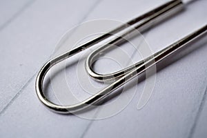 Heap of metal paper clips on white lined paper notepad as a symbol of typical office environment