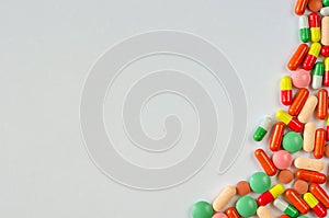 Heap of multi-colored pills, tablets and capsules on a white background. Closeup of medicines. Copy space. Top view