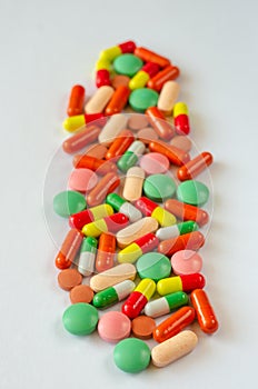 Heap of multi-colored pills, tablets and capsules on a white background. Closeup of medicines. Top view