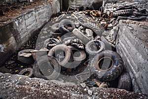 Heap of old car junk tires, used truck rubbish wheels, industrial garbage in abandoned factory