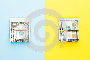 Heap of one dollars banknote and modern hundred us dollar bills on blue and yellow background. Commercial money investment profit