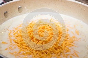 Heap of orange grated cheese in a pan of cream gravy.