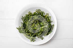 Heap of oven baked crunchy curly kale chips in bowl also known as leaf cabbage.