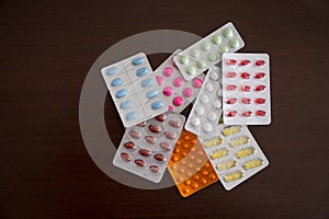 Heap of packs of pills and capsules isolated on brown wooden background