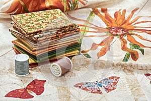 Heap of pieces quilting fabrics lay on cloth with flowers and butterfly images