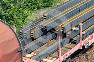 Heap pile heavy raw rusted steel iron beam girders loaded on railroad cargo freight carriage. Metal goods factory plant