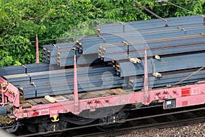 Heap pile heavy raw rusted steel iron beam girders loaded on railroad cargo freight carriage. Metal goods factory plant