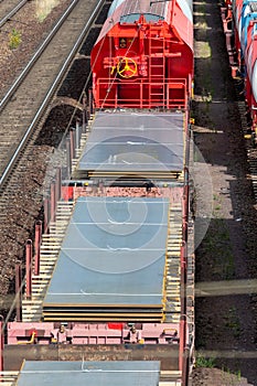 Heap pile heavy raw rusted steel iron sheet plates loaded on railroad cargo freight carriage. Metal goods factory plant