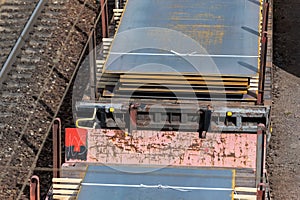 Heap pile heavy raw rusted steel iron sheet plates loaded on railroad cargo freight carriage. Metal goods factory plant