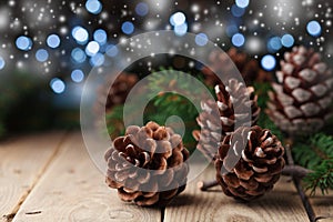 Heap of pine cones and fir tree branch on rustic wooden table. Christmas greeting card.