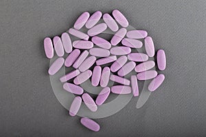 Heap of pink medical pills on a gray background. Health concept photo