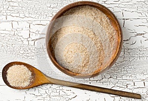 Heap of psyllium husk also called isabgol in wooden bowl and spoon on white table background flat lay from above