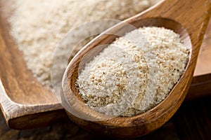 Heap of psyllium husk also called isabgol in wooden spoon and bowl on table