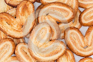 Heap of puff pastry butterfly cookies, top view close-up