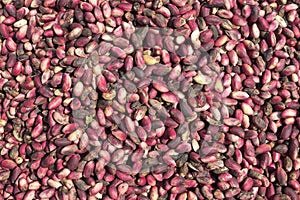Heap of raw fresh pistachios with outer shells at the market.
