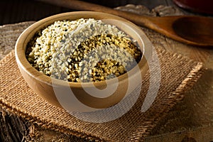 Heap of raw, organic hemp seeds in wooden bowl on burlap on rust
