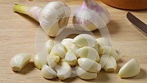 Heap of raw peeled garlic with fresh picked garlic in the background