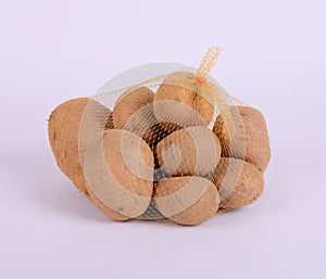 Heap of raw potatoes in yellow string bag