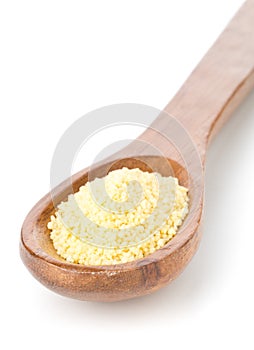 Heap of raw, uncooked couscous in wooden spoon over white