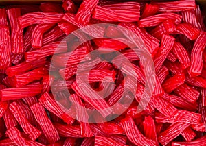 Heap of red strawberry licorice twizzlers red vine candies at supermarket. Creative sweet food confectionery pattern. Kids treats