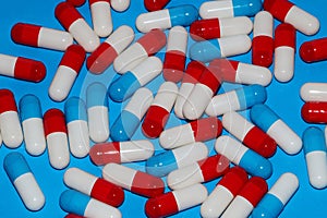 Heap of red white capsules lie on a blue background in the studio