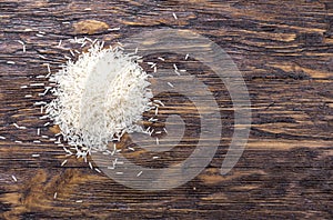 Heap of rice on wooden table, top view