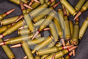 Heap of the rifle cartridges on a black textile surface