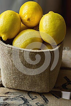 Heap of Ripe Organic Lemons in Jute Sack Standing on Wood Garden Box. Rustic Kinfolk Style. Atmospheric Mood Cozy Atmosphere.