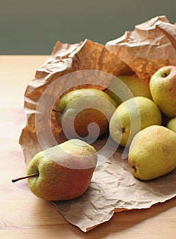 Heap of ripe pears on wooden table rapped in paper