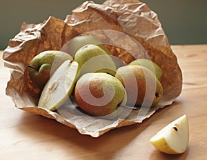 Heap of ripe pears on wooden table rapped in paper