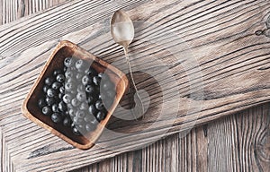 Heap ripe sweet blueberries and spoon on wooden table top view