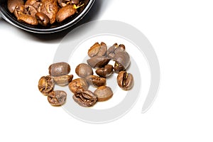 heap of rosted coffee beans on a white background with a plastic spoon.
