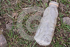 Heap of rubbish on grass in sunny park, plastic bottles, bottle caps and paper, concept of environmental protection, littering of