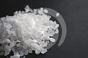 Heap of sea salt on black surface