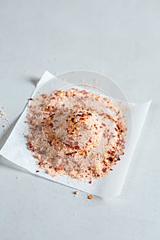 A heap of sea salt with chilli flakes on piece of paper