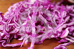 Heap of shredded fresh red cabbage on wooden table, closeup