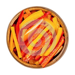A heap of sliced bell peppers, sweet peppers, capsicum in a wooden bowl