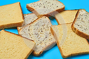 Heap of square pieces of bread with seeds and vanilla for toast lies on blue table on kitchen