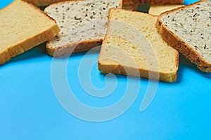 Heap of square pieces of bread with seeds and vanilla for toast lies on blue table on kitchen