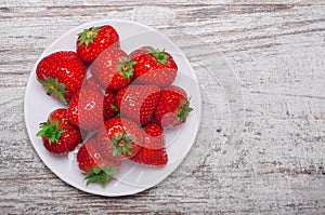 Heap of strawberries in bowl on old wooden background. Top view.