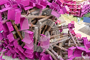 A heap of support material steel covering by pink rustproof paint, on the concrete floor in front the building in construction