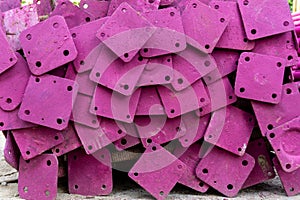 A heap of support material steel covering by pink rustproof paint, on the concrete floor in front the building in construction