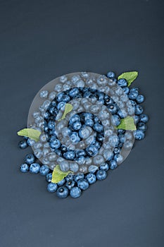 A heap of sweet and natural blueberries with mint on a dark blue background. Organic ingredients for healthy snacks.