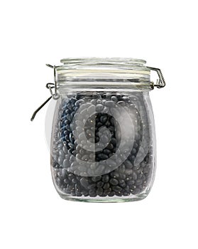 Heap of uncooked black beans grains in glass storage jar isolated on white background