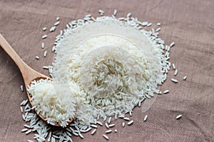 Heap of uncooked Thai Rice in wooden spoon