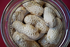 Heap of unpeeled goober nuts (monkey nuts or also called groundnuts) in the glass container